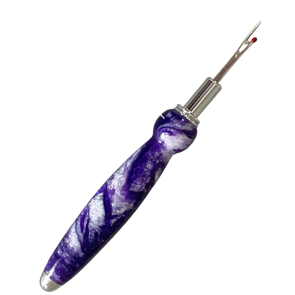 Hand  turned seam ripper using purple and white resin and a chrome blade on a white background.  Made by Paul’s hand turned creations. 