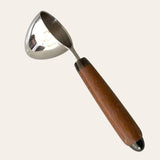 A chrome hand-turned coffee scoop with a handle made from Brazilian Cherry wood on a plain background. 