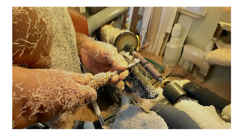 Image showing Paul's hands turning on his lathe with two pieces of wood and shavings on him Paul's Hand Turned Creations. 