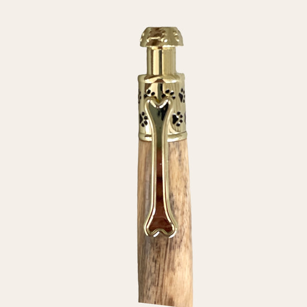 A detailed view of the Spalted Tamarind Dog Click Pen With Gold Trim from Paul's Hand Turned Creations. The pen boasts intricate gold accents and a spalted tamarind wooden body. The elegant design and gold clip make it an exquisite personalized accessory, showcased against a plain, light background.