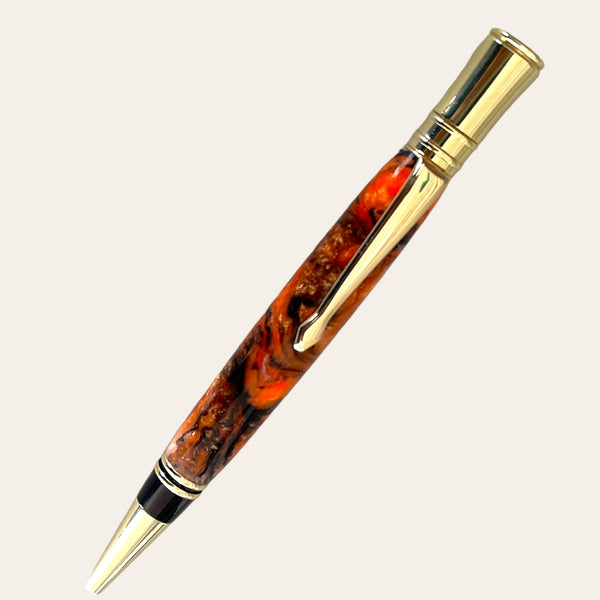 Introducing the Executive Pen With Gold Trim- Tangerine by Paul's Hand Turned Creations. This luxury pen showcases a gold-plated clip and tip, adorned with a glossy marbled design in shades of orange, brown, and red. Embodying handcrafted excellence, it offers a sophisticated appearance coupled with a smooth writing experience.