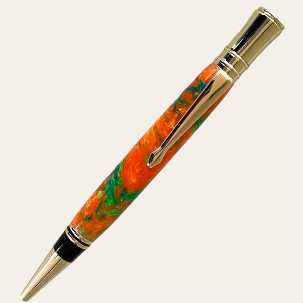 The Resin Executive Pen With Chrome Trim - Harmony by Paul's Hand Turned Creations is a handcrafted writing instrument featuring a vibrant swirling orange and green barrel. This sleek and elegant pen boasts chrome accents, including the clip, tip, and band near the top. Its glossy finish provides an added touch of sophistication. Designed with ergonomics in mind, the pen is positioned diagonally for comfortable use.