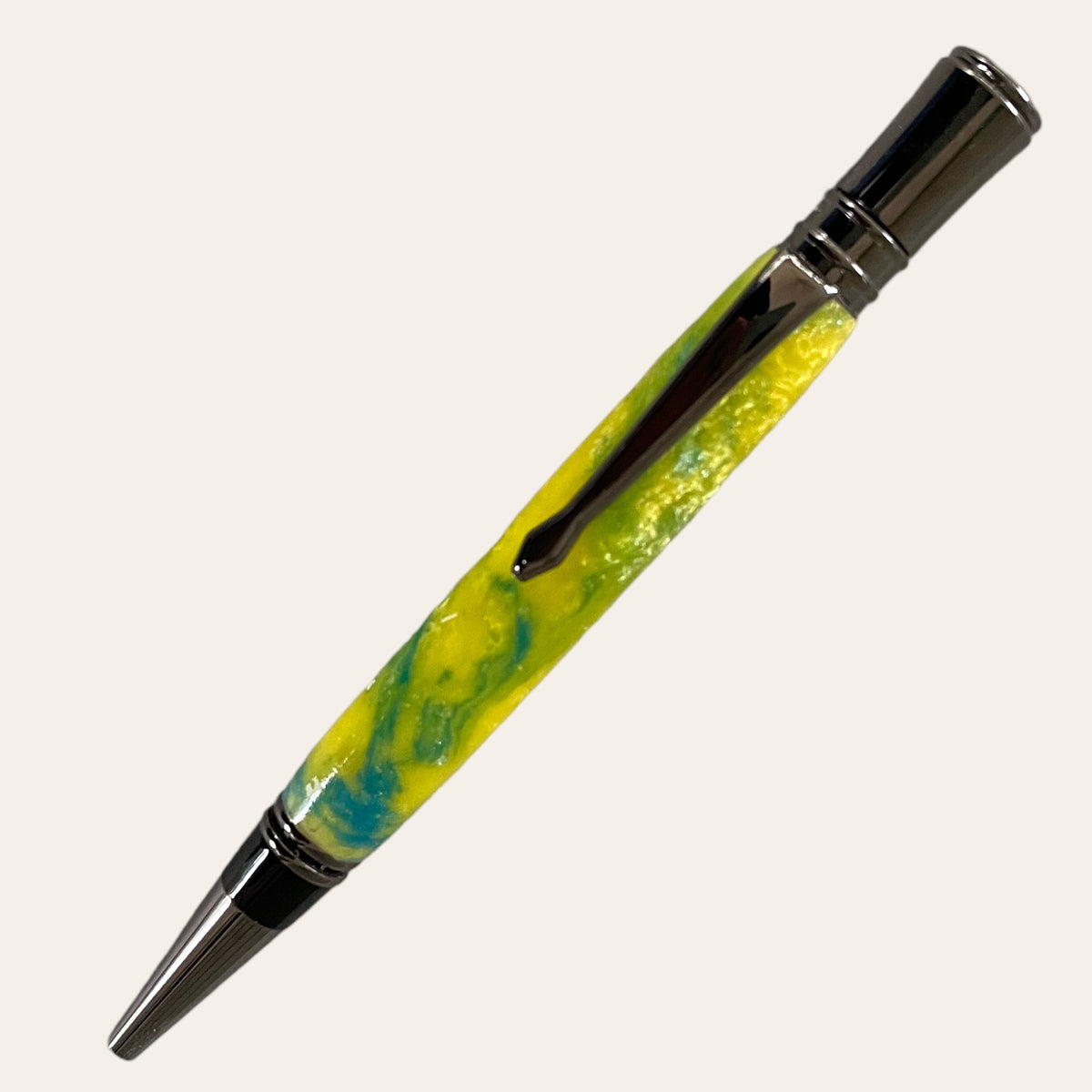 The Hand Turned Executive Pen With Gun Metal Trim - Sunbeam by Paul's Hand Turned Creations features a metal tip and cap. The pen's body showcases a shiny, marbled design in yellow and blue, seamlessly blending to create a vibrant pattern. The gun metal finish on the cap and tip enhances the polished look of this handmade piece, which uses Parker-style refills.