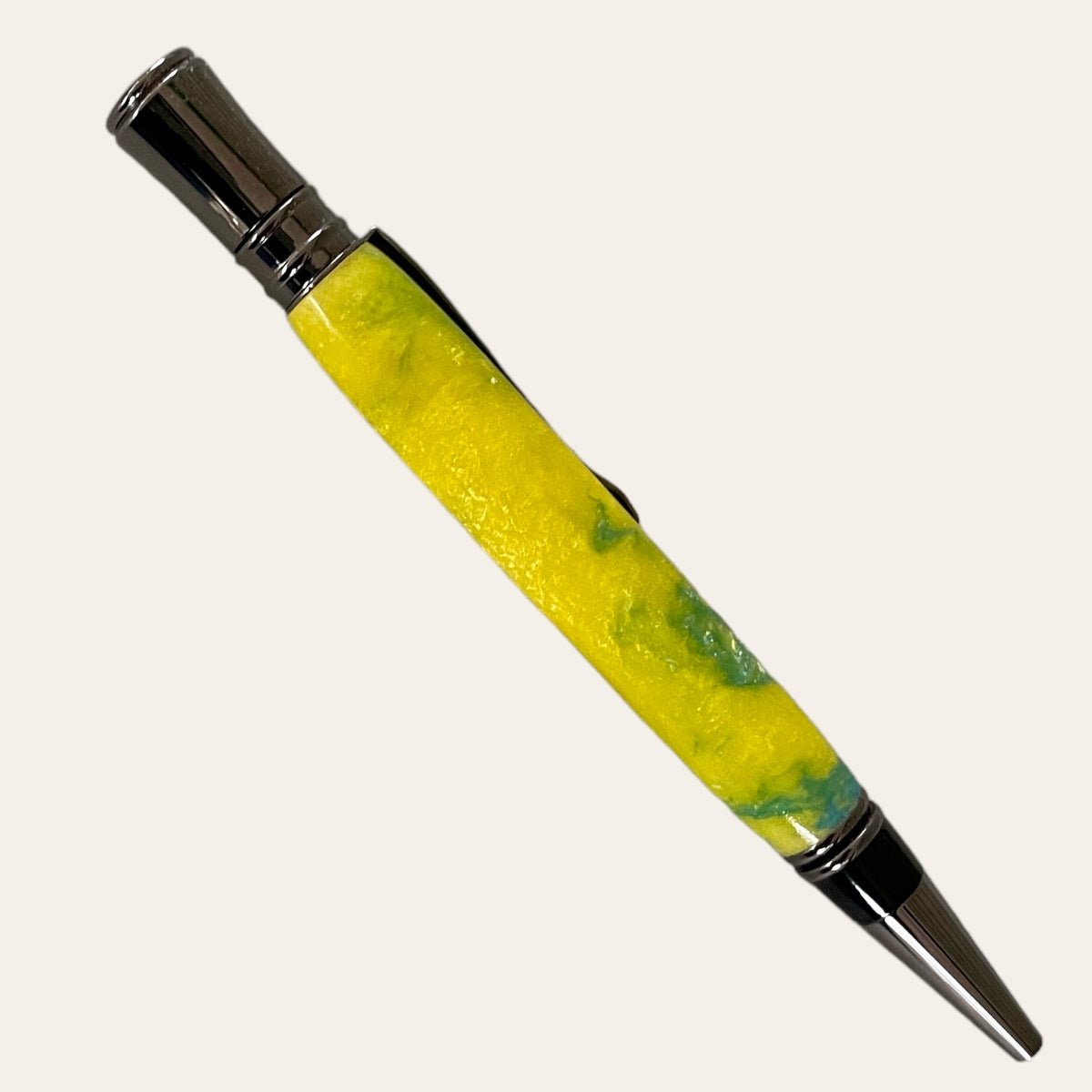 The Hand Turned Executive Pen With Gun Metal Trim - Sunbeam from Paul's Hand Turned Creations features a striking yellow and green marbled resin body, complemented by its metallic silver tip and clip. This handmade twist pen uses a Parker-style refill and is showcased diagonally against a plain, off-white background.