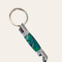 Introducing the Chrome Hand Turned Bottle Opener Resin Keychain- Peacock by Paul's Hand Turned Creations: This stylish bottle opener keychain features a metallic loop attachment and a cylindrical handle adorned in a captivating green and blue marbled pattern. The sleek design is enhanced with silver accents, a textured grip, and durable chrome trim, making it both functional and elegant.