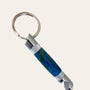 A close-up of the Paul's Hand Turned Creations Chrome Hand Turned Bottle Opener Resin Keychain- Under The Sea, showcasing its cylindrical, metallic body with a blue and green marbled pattern in the center. This stylish accessory features a solid silver-colored ring at the top, durable chrome trim, and a silver dual-pronged tool at the bottom.