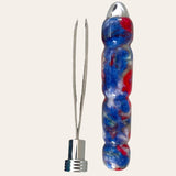 The Hand Turned Resin Case With Tweezer - Psychedelic by Paul's Hand Turned Creations features a marbled blue, red, and white handle with convenient grip indentations and a metal cap on one end. Removing the cap unveils two stainless steel tweezer prongs. The backdrop is a solid off-white color.