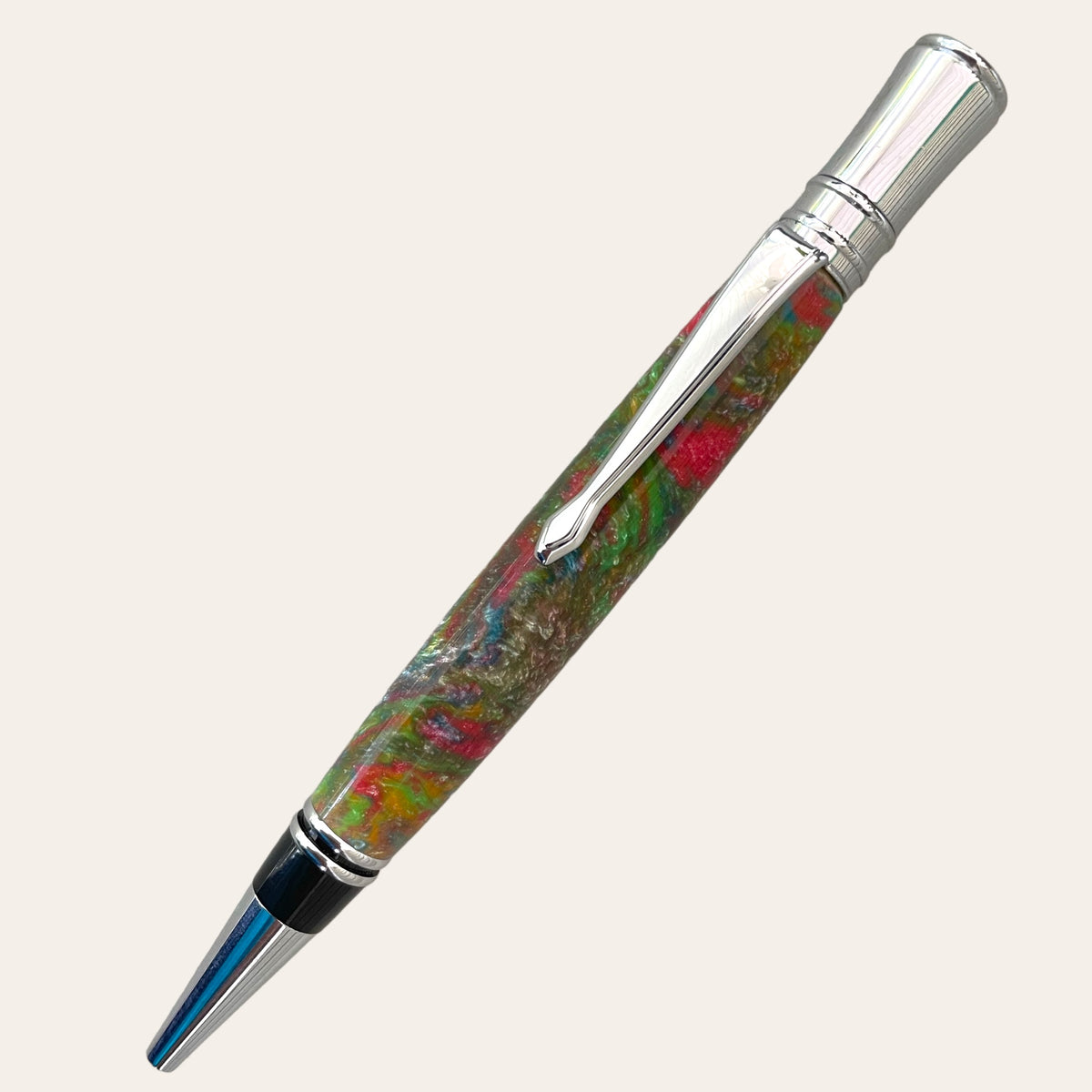 Introducing the Refillable Resin Executive Pen With Chrome Trim - Mysterious from Paul's Hand Turned Creations. Featuring a vibrant marbled barrel in mesmerizing shades of green, red, and brown, this executive twist pen is accentuated with elegant chrome trims on the tip, clip, and cap. Equipped with a Parker-style refill for smooth writing performance against a neutral off-white background.