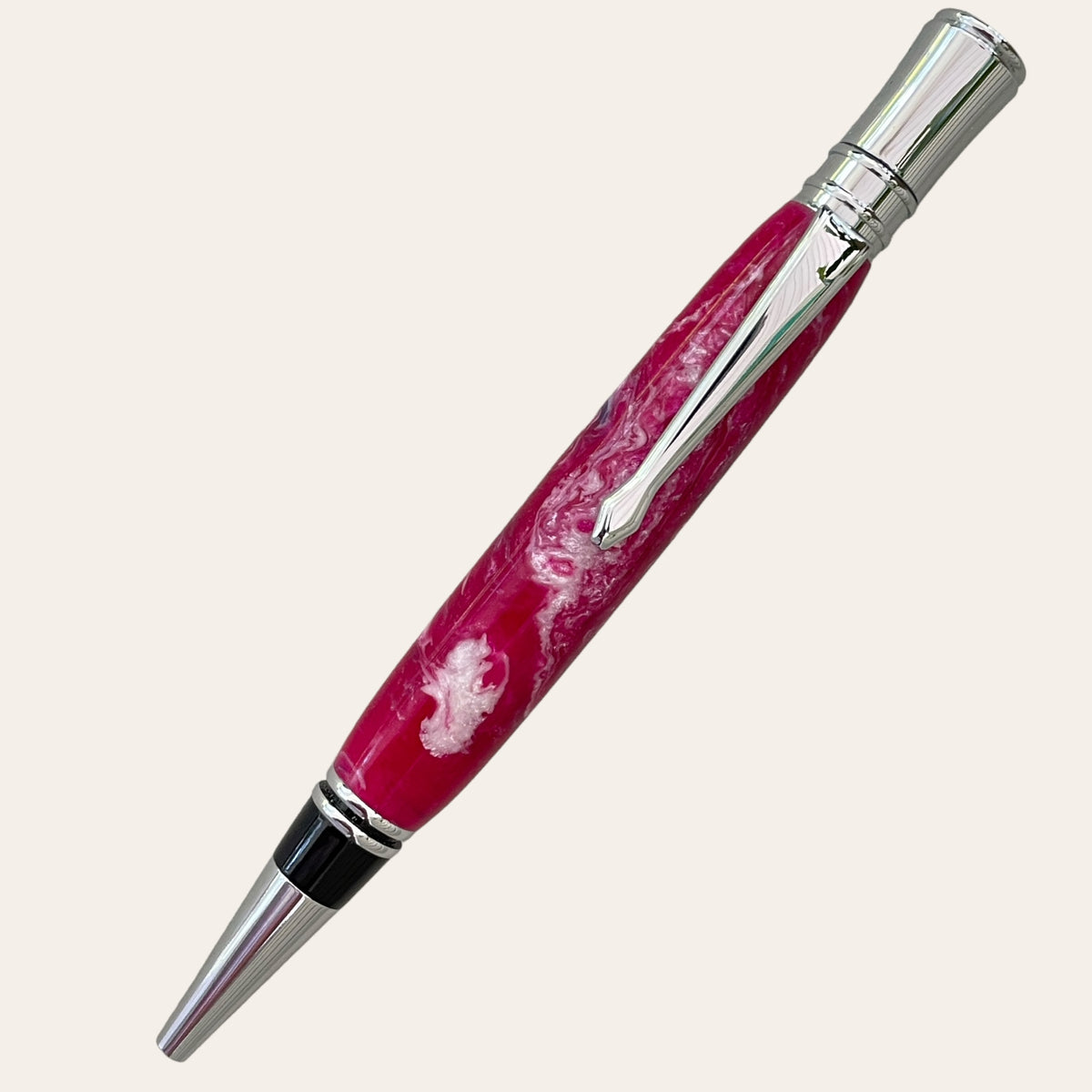 Introducing the Refillable Resin Executive Pen With Chrome Trim - Magenta from Paul's Hand Turned Creations. This exquisite pen features a chrome clip and tip, with a body showcasing a mesmerizing swirl of white and shades of magenta for a marbled appearance. Handmade on a lathe, it utilizes a Parker-style refill to ensure an elegant writing experience against any backdrop.
