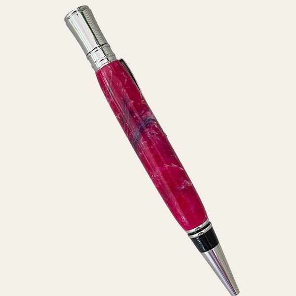 A sleek, handcrafted ballpoint pen with a vibrant magenta marbled body. This Refillable Resin Executive Pen With Chrome Trim from Paul's Hand Turned Creations features polished chrome accents, including the clip, tip, and cap. The marbled design creates a luxurious and artistic appearance. Compatible with Parker-style refills. Background is plain light beige.