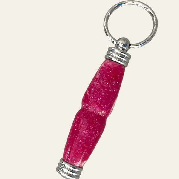 A Magenta Hand Turned Resin Secret Compartment Key Chain with a pink glittery handle, meticulously crafted by Paul's Hand Turned Creations.