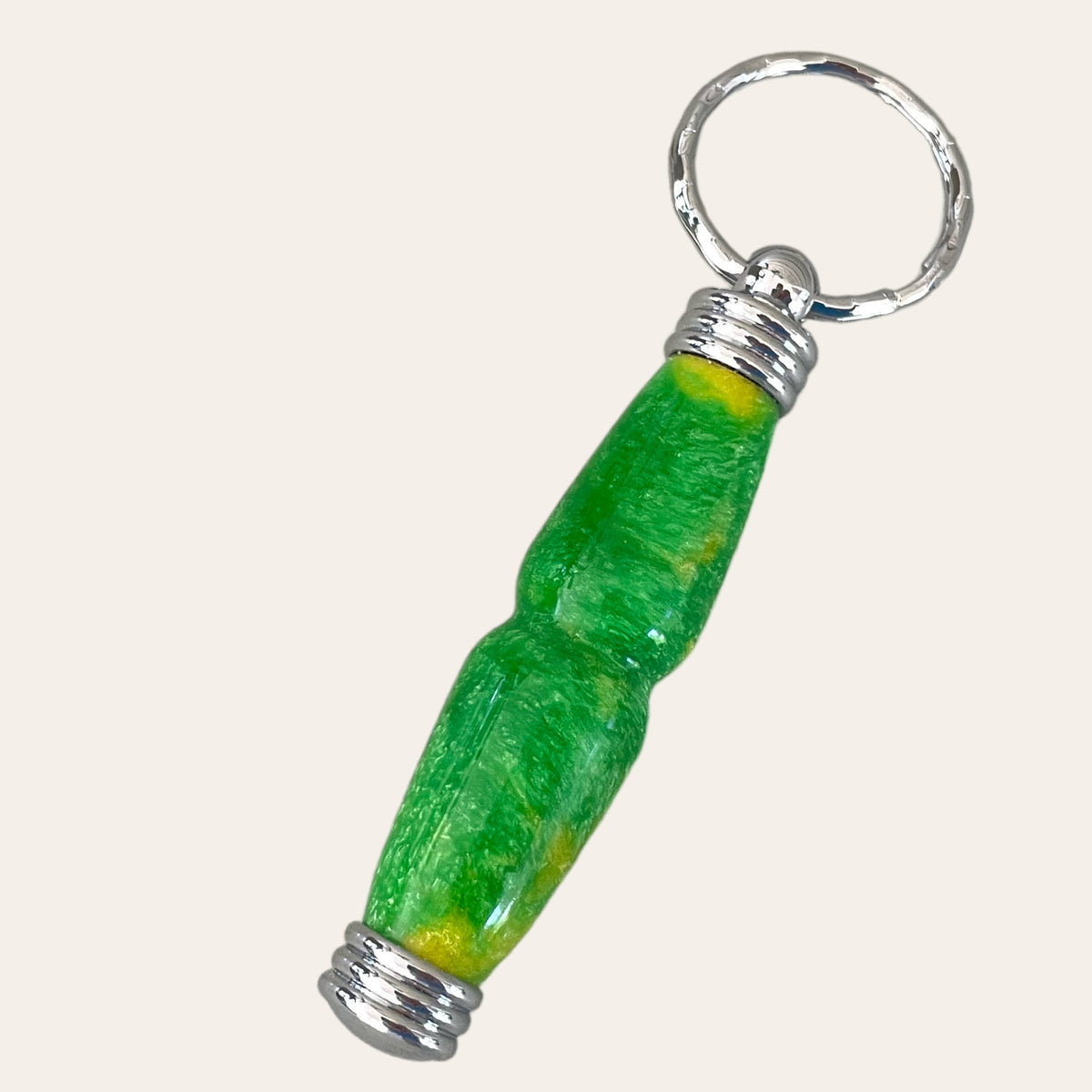 Introducing the **Hand Turned Resin Secret Compartment Key Chain - Lemon Lime** by **Paul's Hand Turned Creations**. This vibrant keychain showcases a striking green and yellow design, complete with metallic silver ring and end caps. It features a slightly curved, elongated shape, a glossy finish, and is meticulously crafted from durable resin.