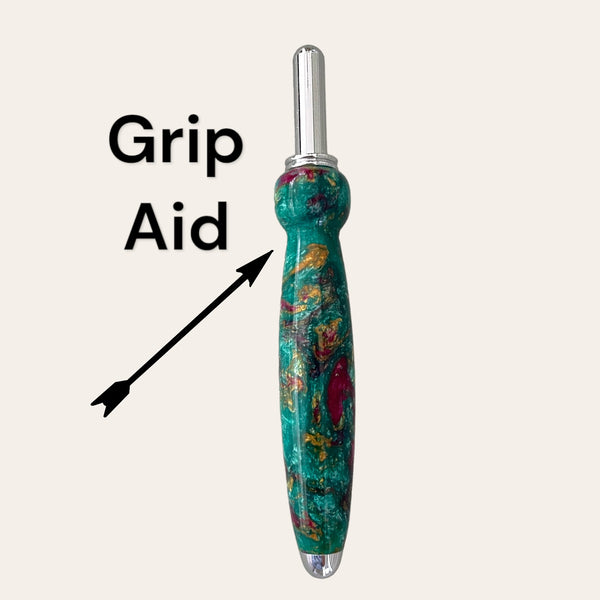 An image of the Royal Jewels Resin Single Blade Seam Ripper, a grip aid tool from Paul's Hand Turned Creations, featuring a shiny metal top and a handle with green, red, and gold swirls. The tool is labeled "Grip Aid" with an arrow pointing to it. This versatile sewing tool includes a stainless steel blade for precise cuts.