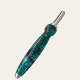 A handcrafted seam ripper made from green, blue, and occasional red resin, with a metallic tip and cap. The Royal Jewels Resin Single Blade Seam Ripper from Paul's Hand Turned Creations has a polished and smooth finish, creating a visually appealing blend of colors. Complementing its artistry like an elegant sewing tool, it stands out against the plain off-white background.