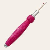 A Magenta Resin Single Blade Seam Ripper from Paul's Hand Turned Creations, featuring a shiny silver blade and a pink marbled handle with a rounded grip for comfortable use, is displayed vertically against a plain white background.