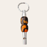 Introducing the Black and Orange Resin Key Chain with Safety Whistle by Paul's Hand Turned Creations. Perfect as a unique gift idea, this small metallic whistle comes with a silver ring attachment and features a distinct handle adorned with swirled patterns in orange, black, and brown hues for a stunning marbled effect. This sleek and polished keychain is not only stylish but also highly practical.