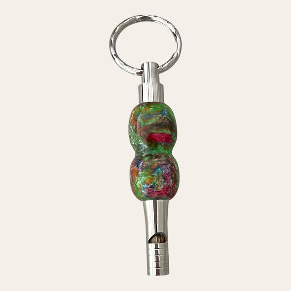 The Multi-Colored Resin Key Chain with Safety Whistle from Paul's Hand Turned Creations features a vibrant handle with a marbled pattern in shades of green, red, and blue, complemented by a metallic silver mouthpiece. This colorful safety whistle also includes a ring for easy attachment to your keychain, making it both functional and a unique accessory.