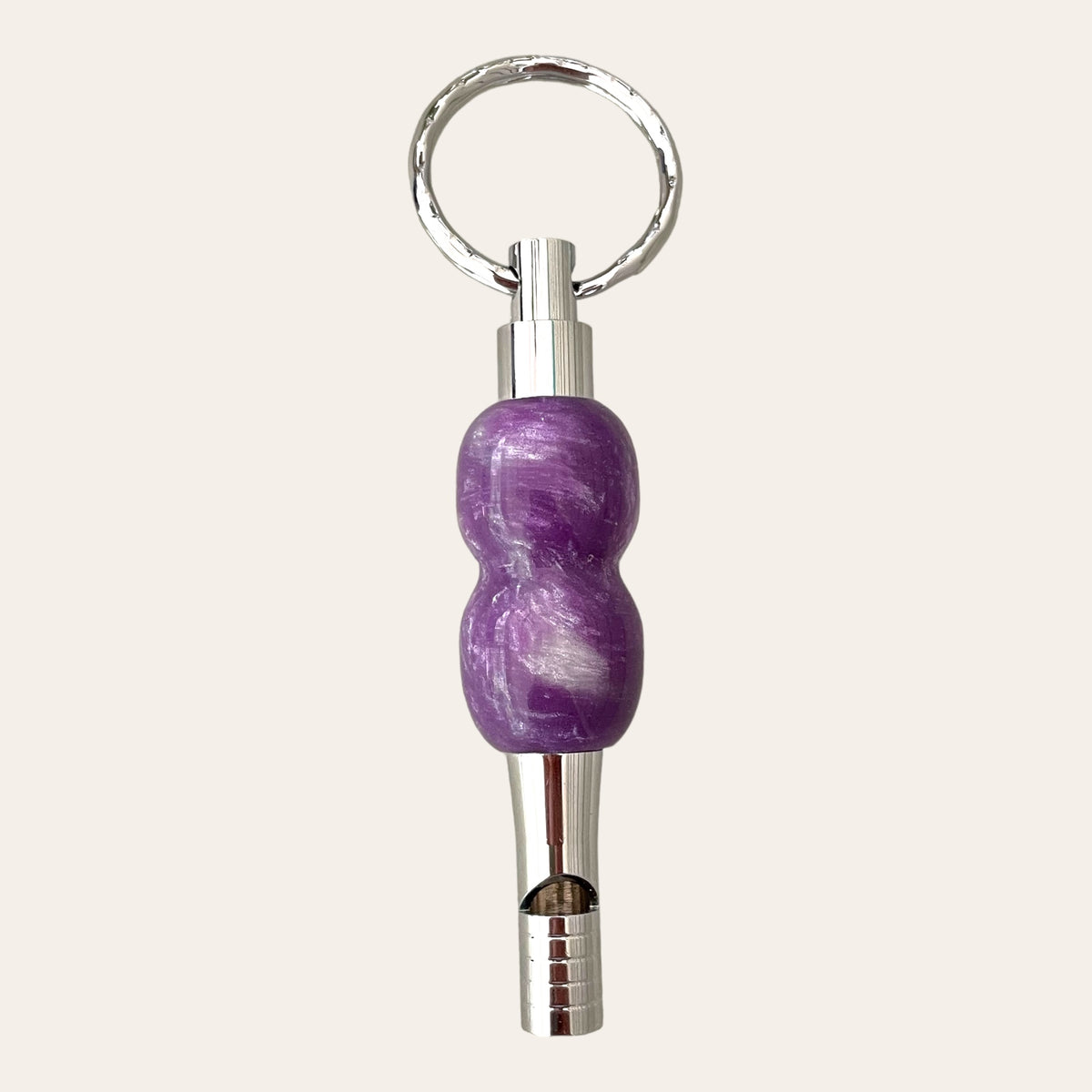 Introducing the Lilac Resin Key Chain with Safety Whistle from Paul's Hand Turned Creations: A sophisticated metal whistle attached to a sleek, circular silver keyring, doubling as a unique and functional accessory. The handle showcases a captivating marbled purple design with a glossy finish, making this not just a stylish addition to your keys but also an essential safety tool.