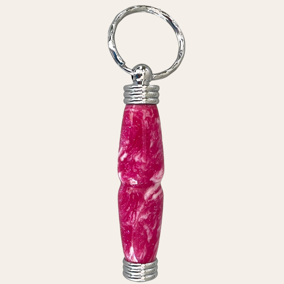 A close-up image of the Magenta Hand Turned Resin Secret Compartment Key Chain by Paul's Hand Turned Creations features a cylindrical design in a rich magenta hue. The body of the keychain is slightly contoured, with metallic silver caps on both ends and a silver ring attached at the top.