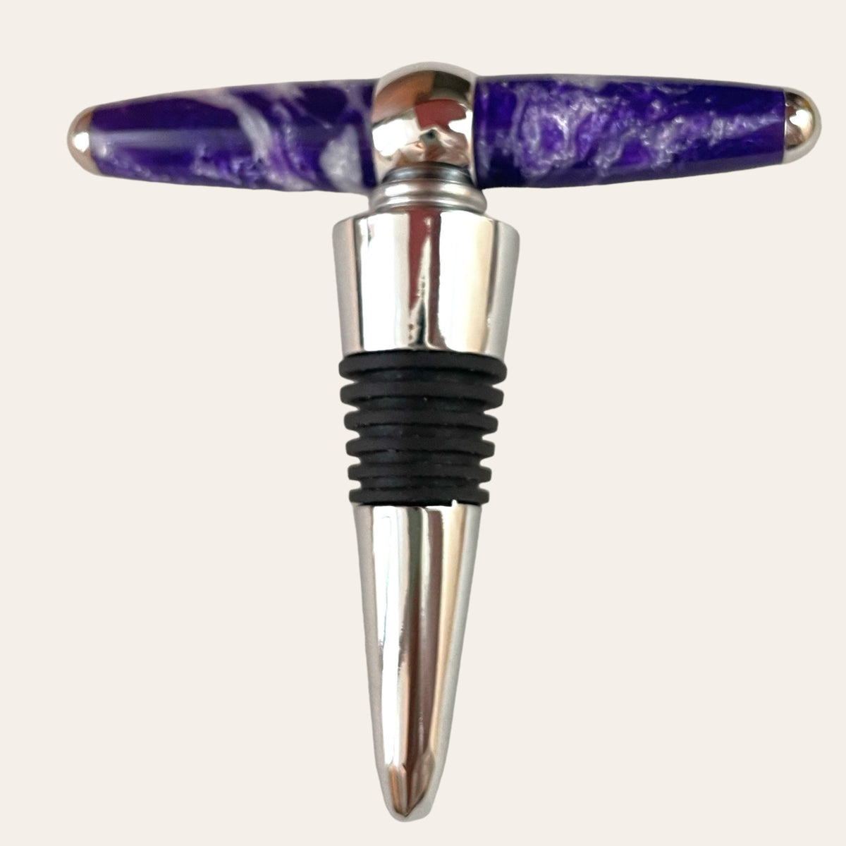 Introducing the T-Handle Wine-topper With Built-in Corkscrew - Purple Passion by Paul's Hand Turned Creations: a handmade bottle stopper featuring a silver base and a black rubber stopper. The handle, crafted horizontally from a shiny material in vibrant purple with white marbling, adds a touch of elegance. This versatile piece also functions as a dual wine topper against an off-white background.