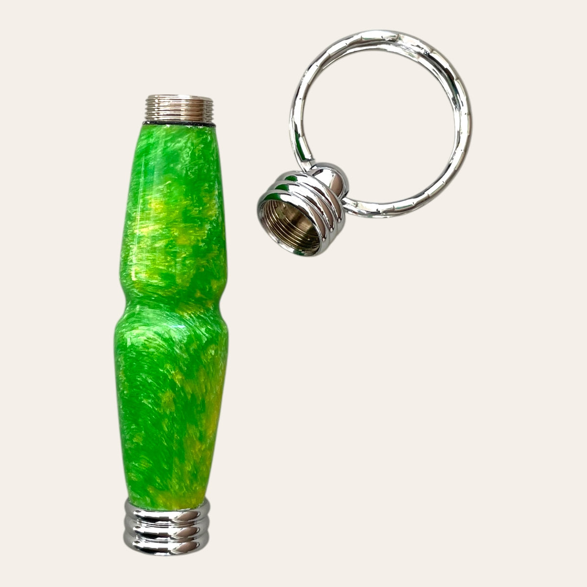 The Hand Turned Resin Secret Compartment Key Chain - Lemon Lime by Paul's Hand Turned Creations is a small, colorful accessory featuring a textured green and yellow cylindrical body made of durable resin with silver-colored metal ends. The cap can be unscrewed to reveal the threaded opening next to the Secret Compartment Key Chain. It includes a silver ring for easy attachment to keys or other items.