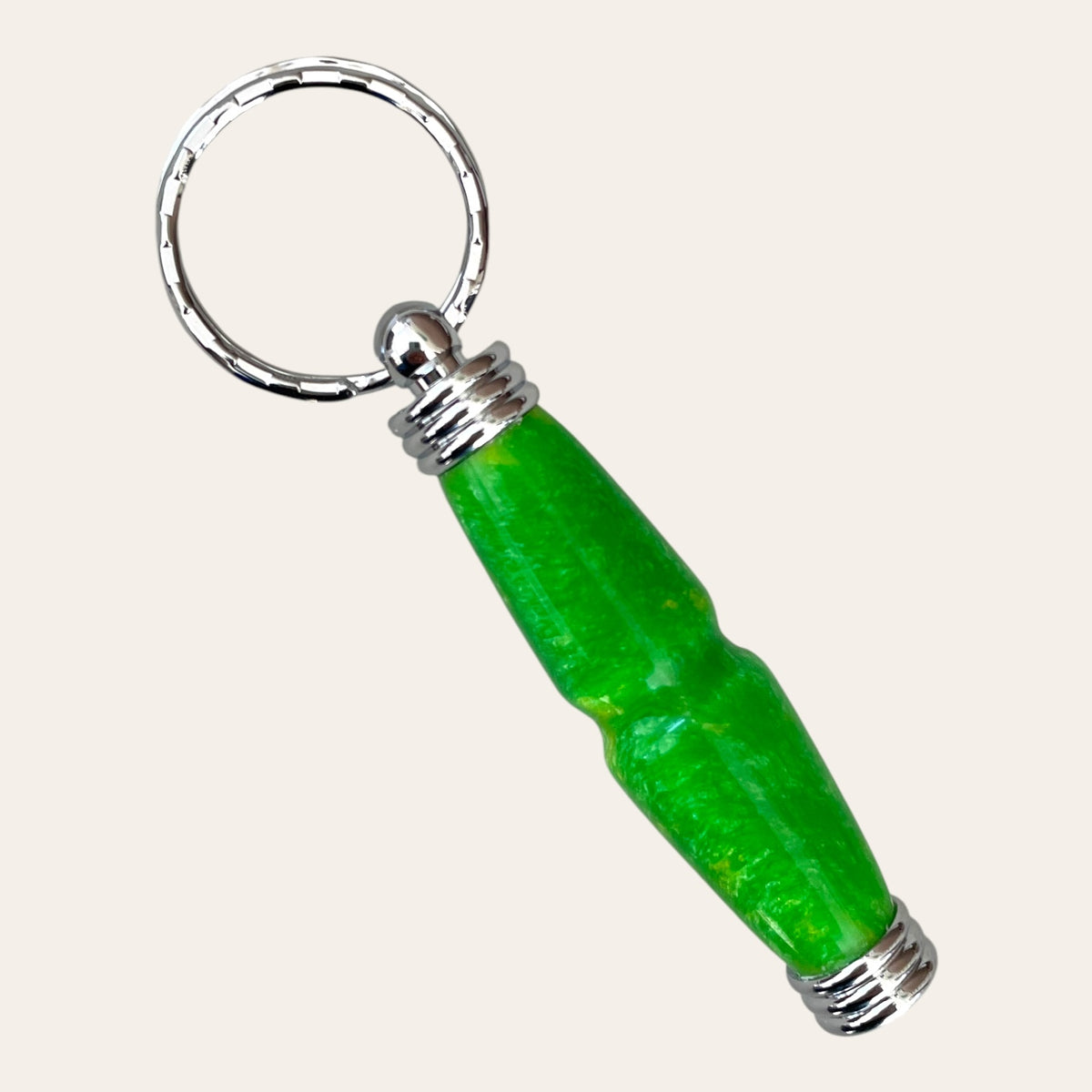 Introducing the **Hand Turned Resin Secret Compartment Key Chain - Lemon Lime** by **Paul's Hand Turned Creations**. This vibrant keychain showcases a striking green and yellow design, complete with metallic silver ring and end caps. It features a slightly curved, elongated shape, a glossy finish, and is meticulously crafted from durable resin.