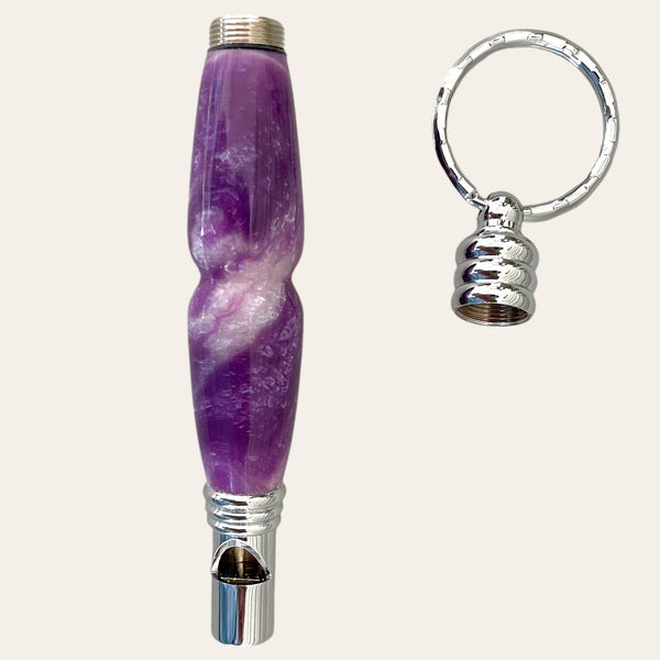 Introducing the Lilac Resin Secret Compartment Key Chain by Paul's Hand Turned Creations, a stylish safety whistle in shades of purple and white, complete with a detachable keychain ring and a convenient secret compartment.