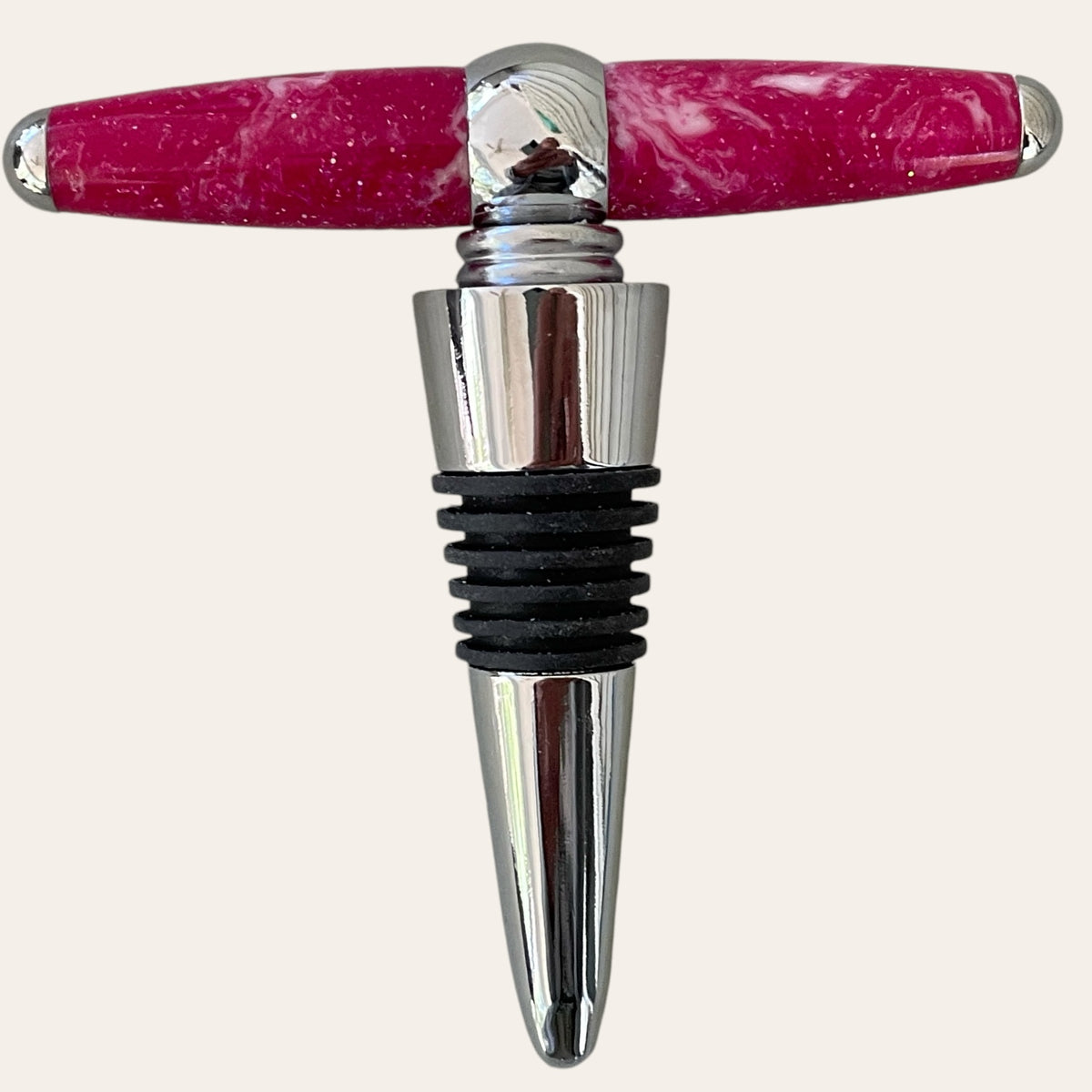 The Magenta Resin Hand Turned T-Handle Winetopper Corkscrew by Paul's Hand Turned Creations is an elegant blend of functionality and style, showcasing a pink, marble-patterned handle.