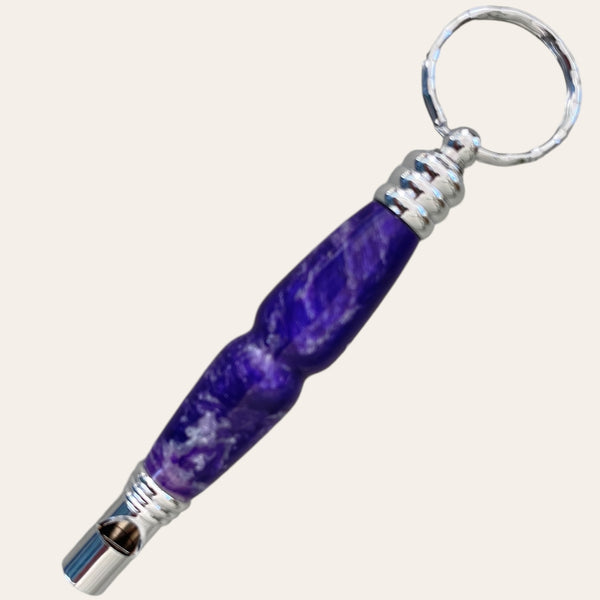 A Purple Passion Secret Compartment Key Chain with Safety Whistle from Paul's Hand Turned Creations features a distinctive purple, marbled handle and a safety whistle attached at the bottom. The simple, metallic keyring complements the unique design of the handle, making it an ideal unique gift.