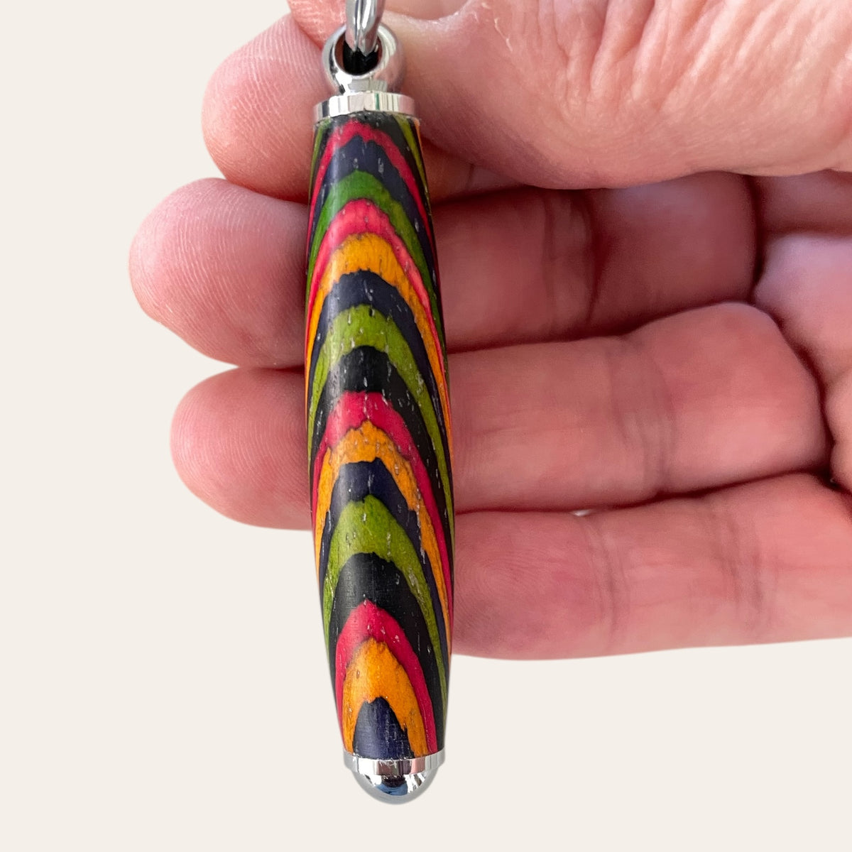 Small Spectraply Wood Keychain by Paul's Hand Turned Creations with metal tips in a hand.